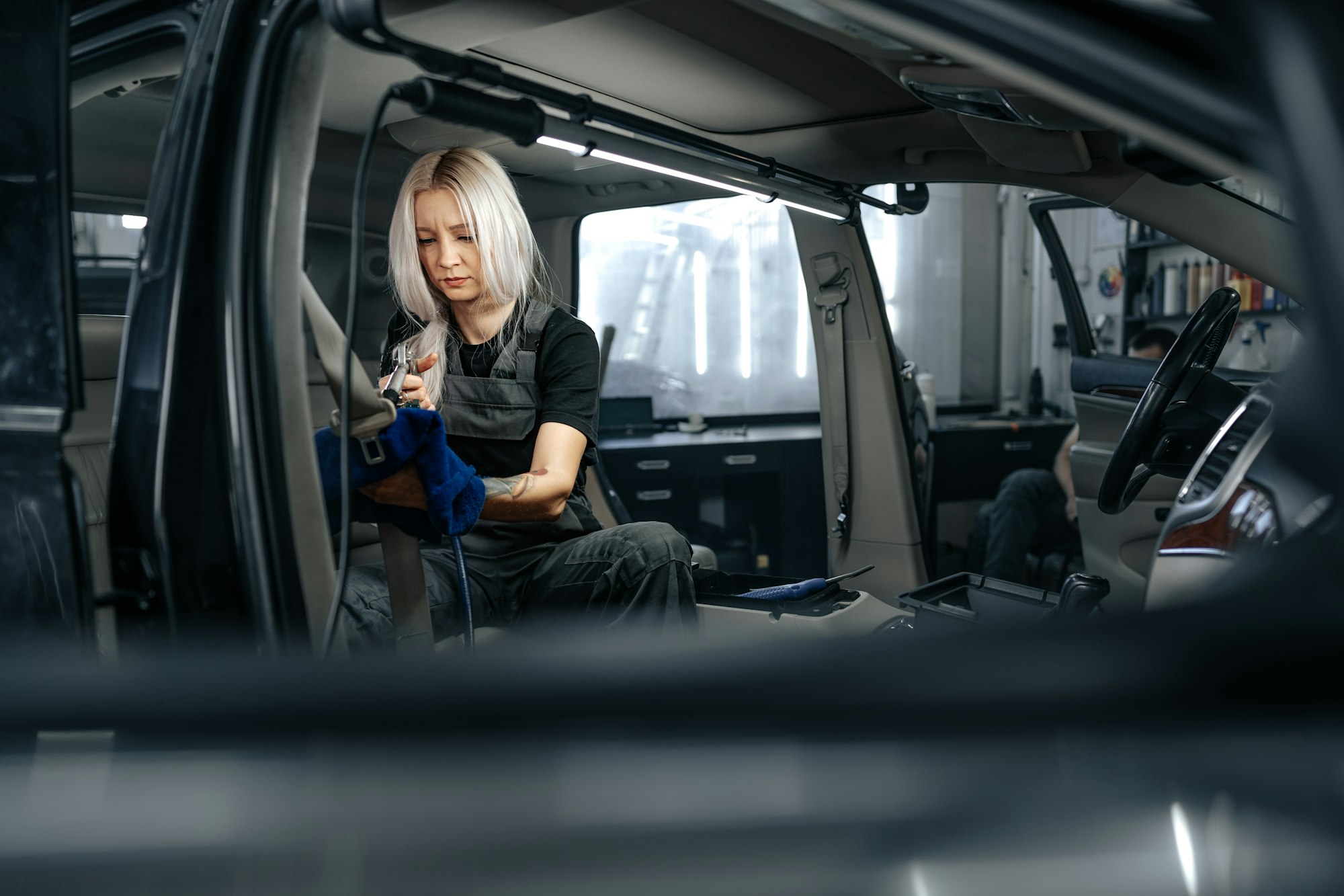 Woman cleaning car salon with polishing spray in car detailing service